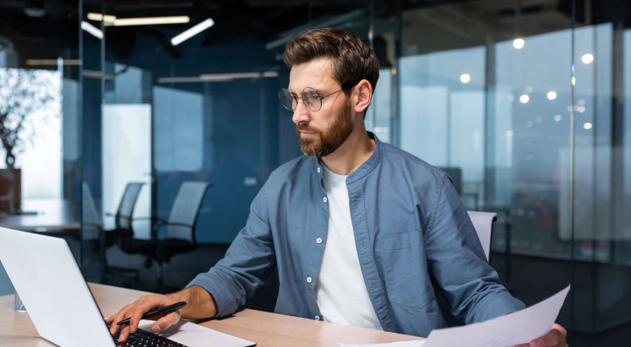 Junger Mann arbeitet in einem Büro am Laptop
