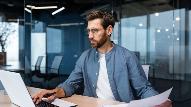 Junger Mann arbeitet in einem Büro am Laptop
